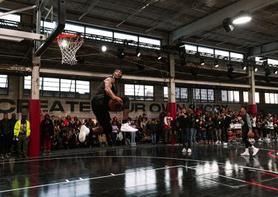 Photo of a basketball player in mid-air on a black basketball court