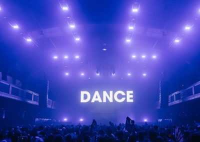 the word dance at an edm show with purple lights